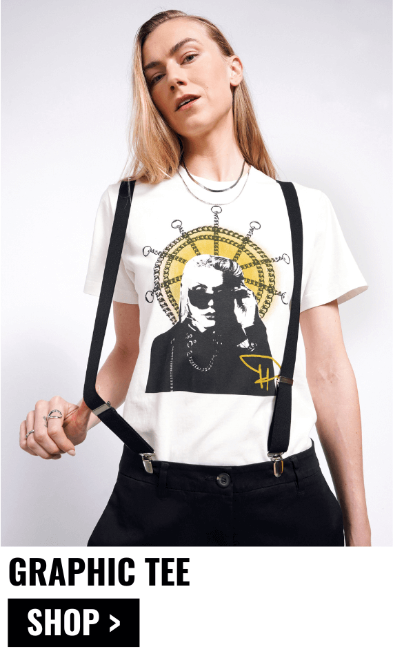 Model with long blonde hair looks at camera wearing suspenders and The Debbie Harry x Wildfang Graphic Tee. Text underneath image reads GRAPHIC TEE $45 and button underneath reads SHOP.