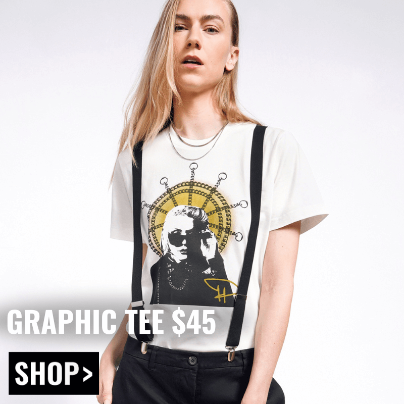 Model with long blonde hair looks at camera wearing suspenders and The Debbie Harry x Wildfang Graphic Tee. Text overlay reads GRAPHIC TEE $45 and button underneath reads SHOP.