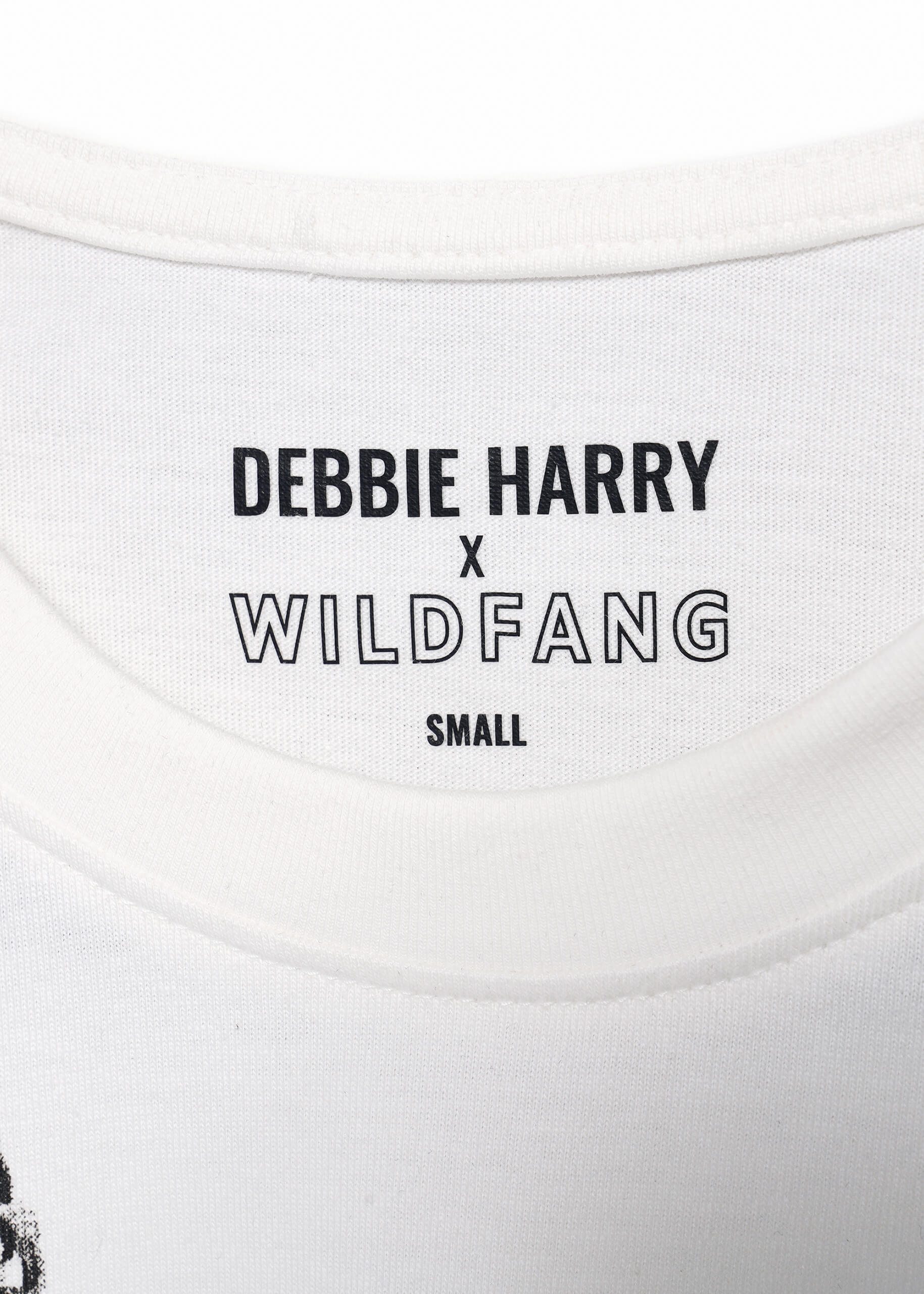 Close-up of the neckline label on a white Debbie Harry X Wildfang Graphic Tee, featuring SMALL beneath, showcasing the punk aesthetic of the collection.