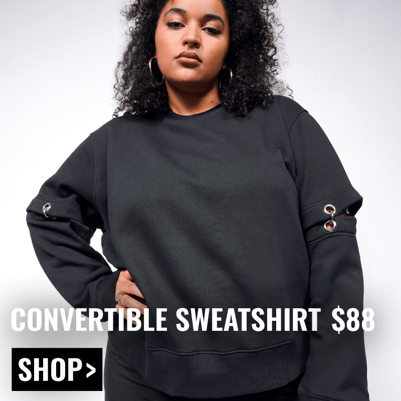 Person with curly black hair wears black Debbie Harry x Wildfang Convertible Sweatshirt and has hair on hip. White background. Text overlay reads CONVERTIBLE SWEATSHIRT $88 and button below reads SHOP.