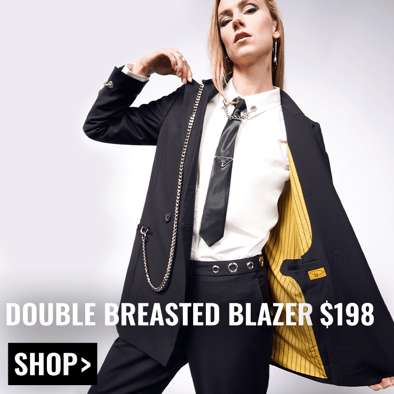 Person with long blonde hair wears the Debbie Harry x Wildfang Double Breasted Blazer with one side open showing the yellow lining. Text overlay reads DOUBLE BREASTED BLAZER $198 with a black button underneath that says SHOP.