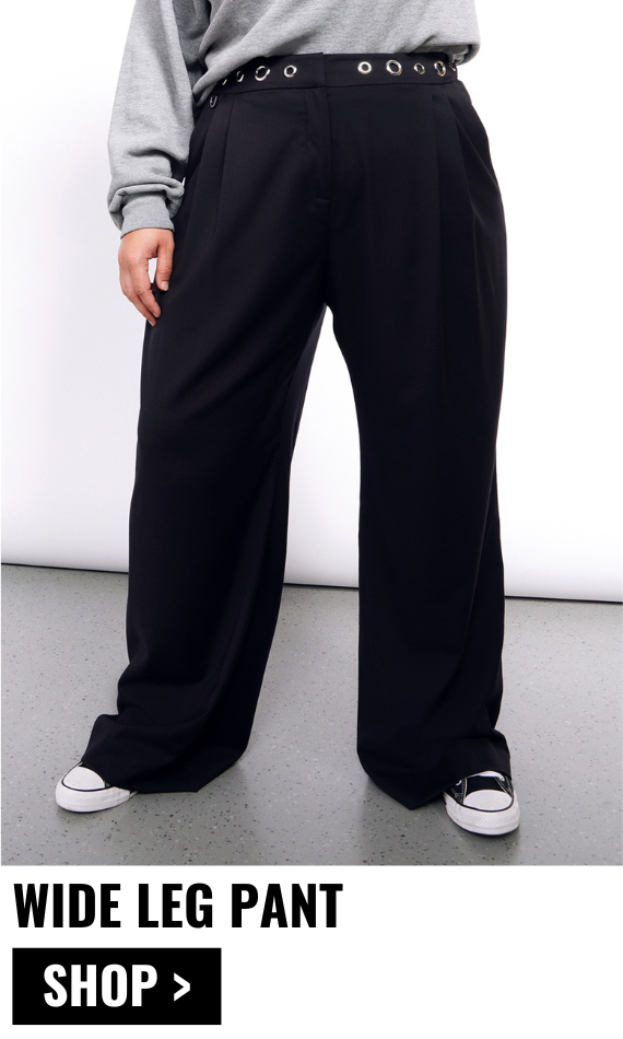 Image shows model from waist down wearing the Debbie Harry x Wildfang Wide Leg Pant in black and converse sneakers. Text underneath image reads WIDE LEG PANT and button below reads SHOP.