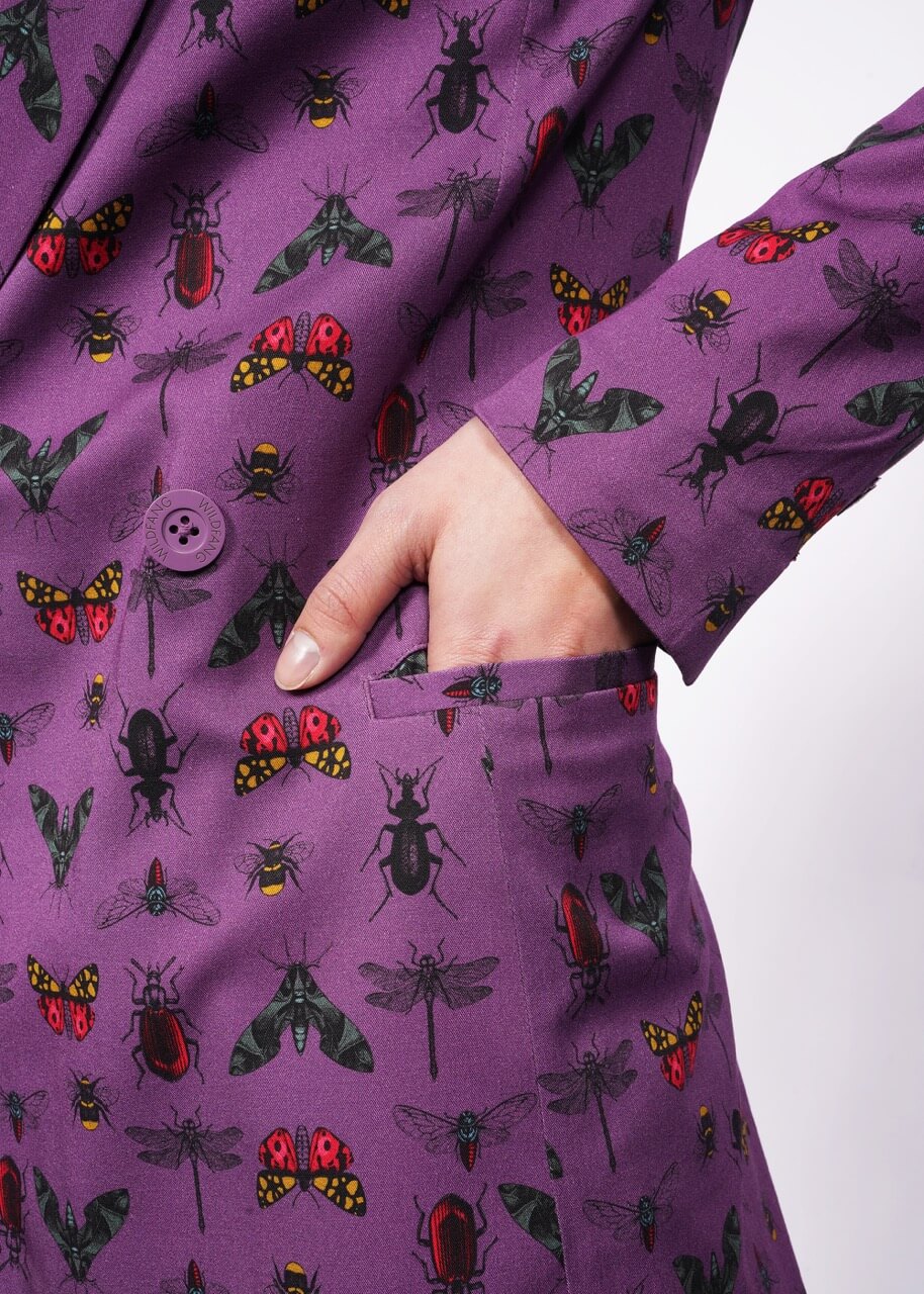 Close up of hand in purple bug printed blazer side picket.