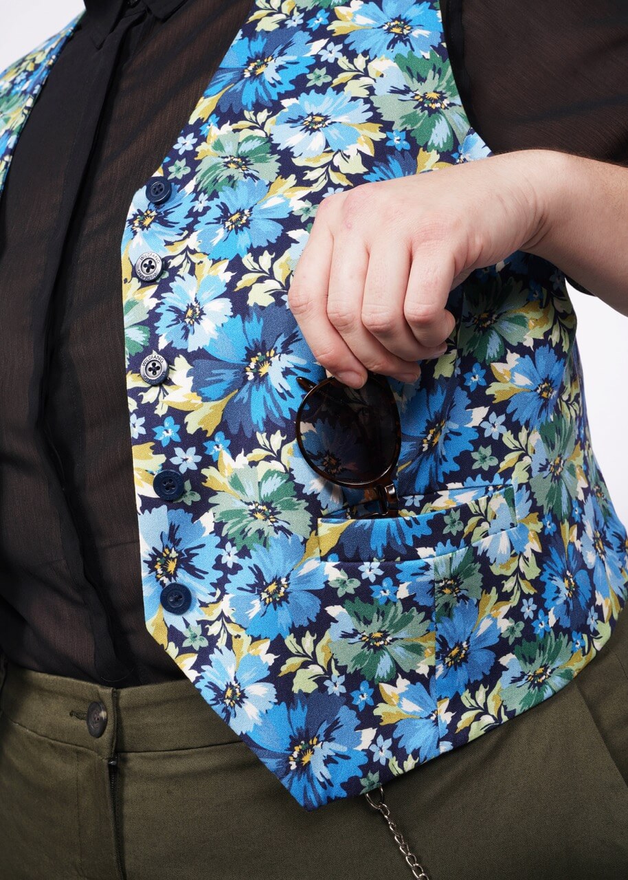 Close up of person putting sunglasses in side pocket of floral printed vest