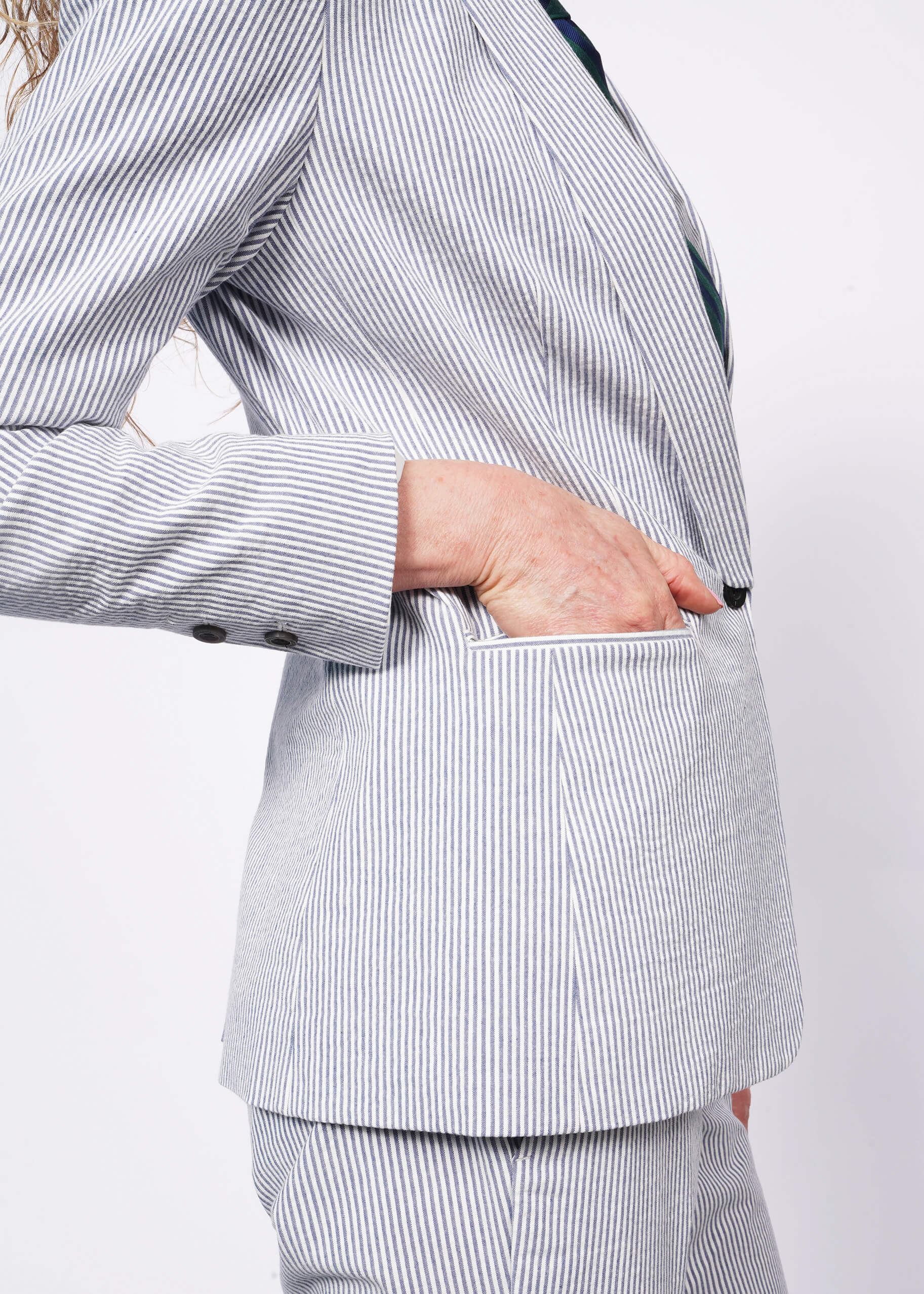 Close up of side view of person wearing seersucker blue and white blazer with matching seersucker trousers.