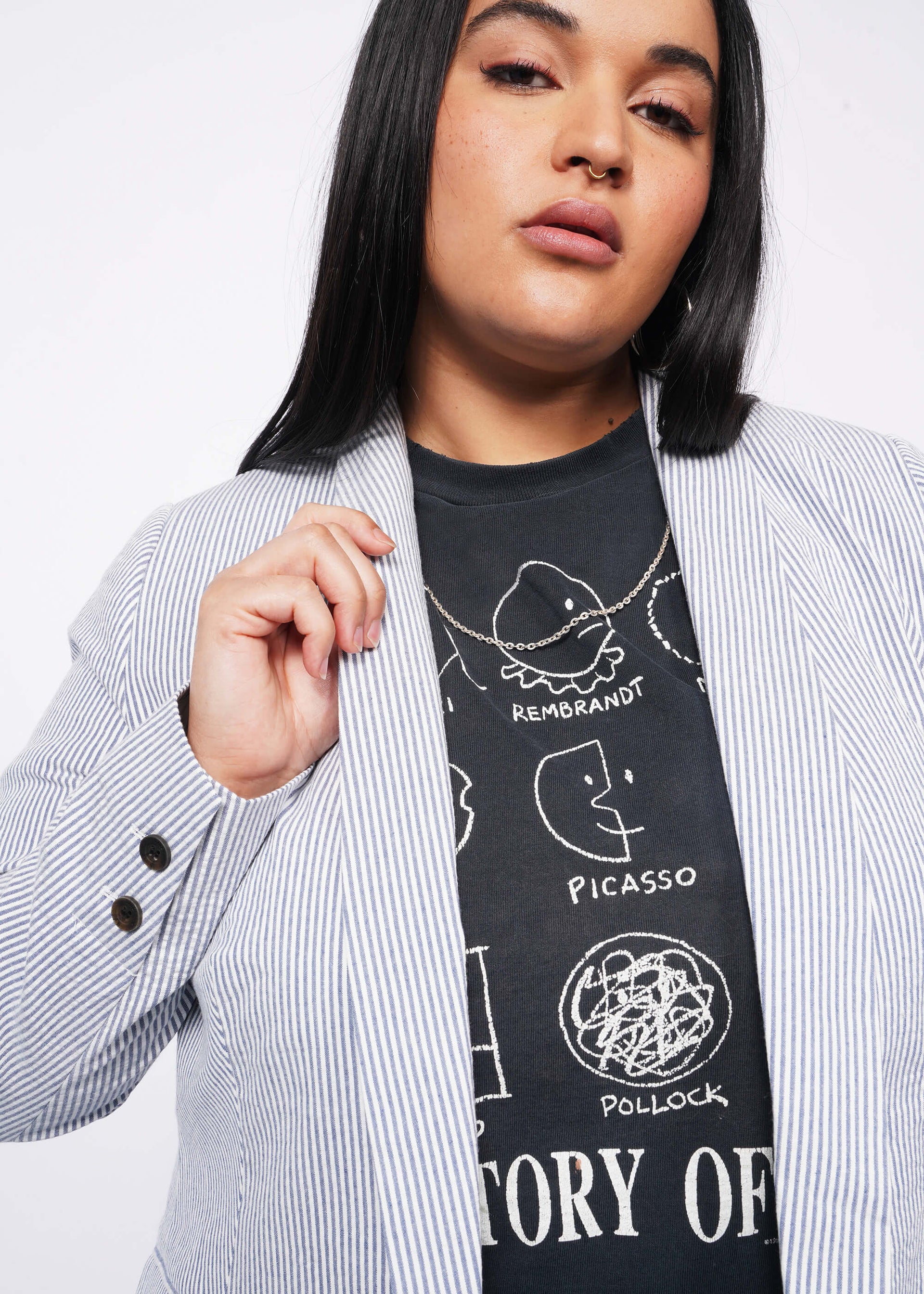 Close up of person with long black hair wears blue and white seersucker blazer over black t-shirt.