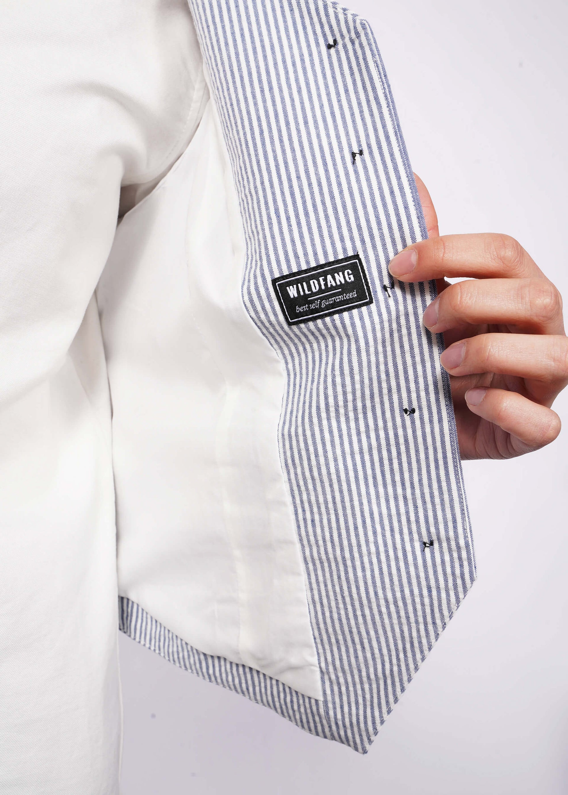 Close up of model holding seersucker blue and white vest open showing lining and WILDFANG tag.