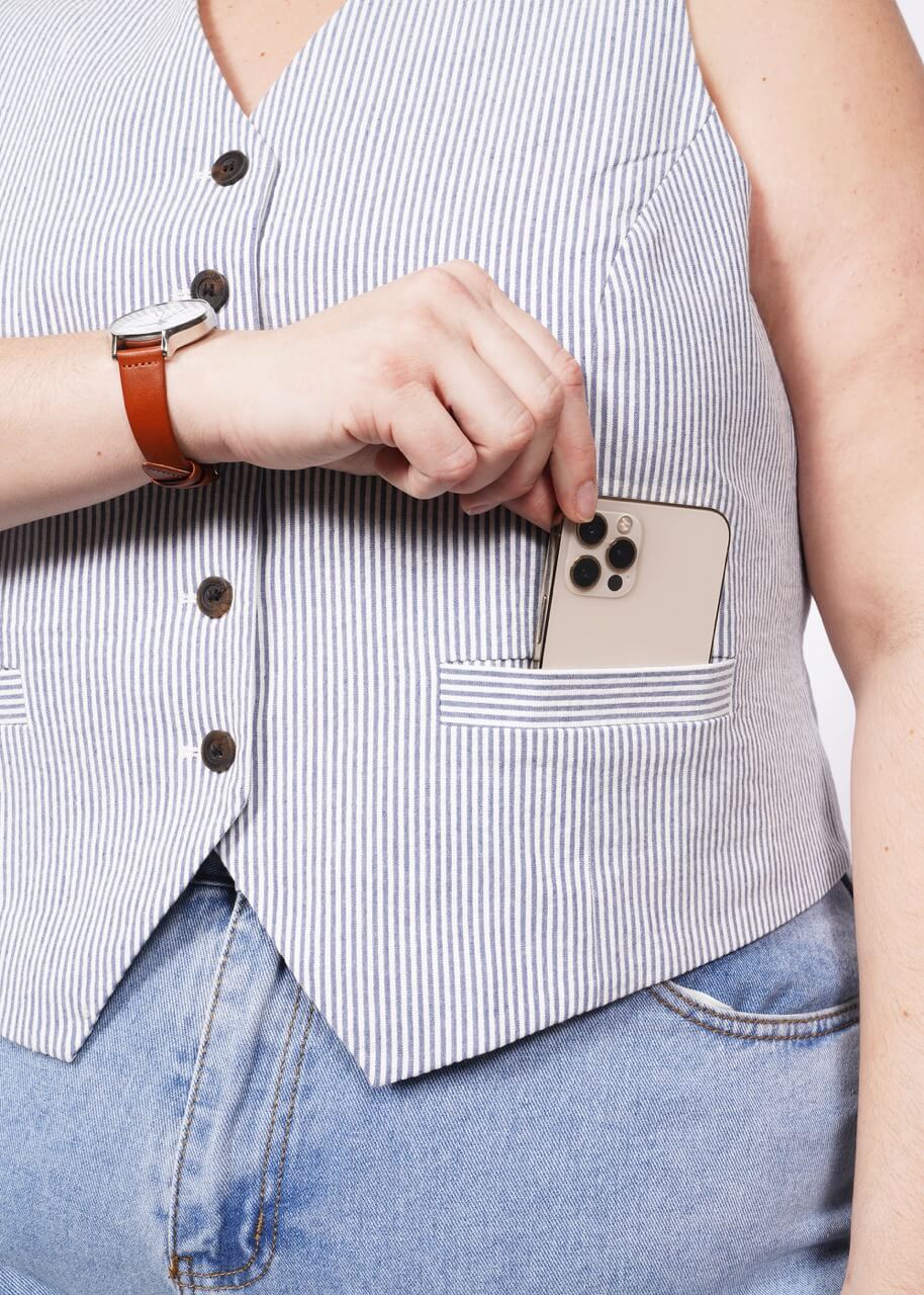 Close up of model putting iphone in seersucker vest pocket.